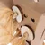 Jouet pour animaux en carton avec disques en bois et lanières de papier, plusieurs trous visibles sur la surface du jouet.