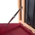 Detailansicht eines Metall-Scharnierarms, der eine Holzklappe mit schwarzer Wand stützt.