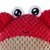 Rood pluchen speelgoed in de vorm van een krabbenkop met geborduurde ogen en mond, beige onderzijde. Gestructureerd oppervlak van zachte stof.