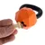 Orangefarvet hundelegetøj i kettlebell-form med sort håndtag, kan fyldes med godbidder. Hånd lægger benformet godbid i åbningen.