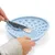 Hand trägt mit Messer Futter auf eine blaue Silikon-Futtermatte mit Noppen auf.