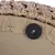 Gros plan sur la fixation d’un panier en tissu beige avec rebord tressé effet rotin, vis et rondelle en métal visibles sous le fond.