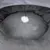 Grey, round pet bed with soft plush interior and hanging white play ball on a string.