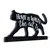 Llavero negro con forma de gato y texto blanco: 'Home is where the cat is'.