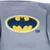 Logo Batman in giallo e blu su tessuto grigio con marchio TM.