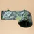 Túnel de tela con estampado de hojas tropicales, borde verde oscuro y forro interior suave. Se ven dos ganchos para fijación.