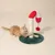 Kratzspielzeug in Zuckerstangenform mit rotem und weissem Stoff, Sisal-Kratzfläche und grünem Standfuss. Rote Bommel als Spielzeug. Katze interagiert mit dem Kratzbereich.