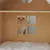 Wooden house with window and soft lying surface, cat looking through the window.