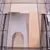 Vista interna di una gabbia con piattaforma in legno e passaggio in plastica, circondata da griglia metallica.