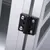 Detaljbild av en svart plastgångjärnsmekanism med fyra silverfärgade skruvar på en aluminiumram.