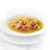 Primer plano de un cuenco con sopa clara que contiene trozos de pollo, zanahorias y hierbas.