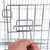 Detailaufnahme eines Metallverschlusses an einem Gitterkäfig, gezeigt mit einer Hand beim Öffnen des Mechanismus.