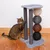 Cat tree with grey cover, three sisal posts and four balls in natural, grey, brown and black. Cat uses one post for scratching.