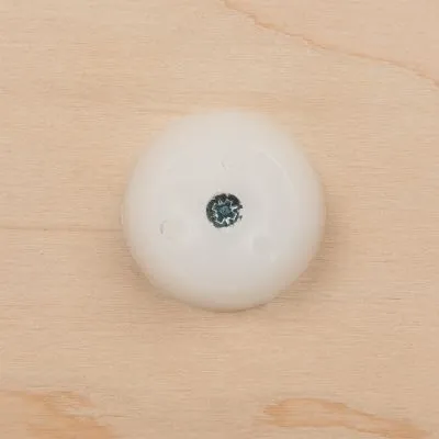 Piedino rotondo in plastica bianca fissato con una vite su superficie in legno chiaro, visto dall'alto.