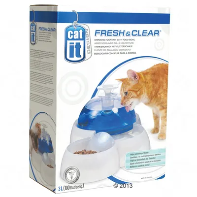 Fuente de agua con comedero para gatos Catit Fresh & Clear, capacidad 3 L. Imagen de un gato bebiendo y texto en varios idiomas sobre beneficios para la salud de las mascotas.