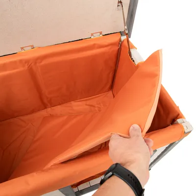 Innenansicht einer orangefarbenen, gepolsterten Box mit abnehmbarem Bezug. Hand hebt den Bezug an, um die Polsterung zu zeigen.