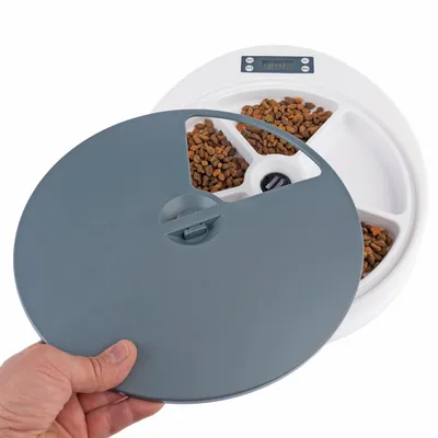 Automatische voerdispenser met digitaal display en afneembaar deksel, toont vier vakken met droogvoer.