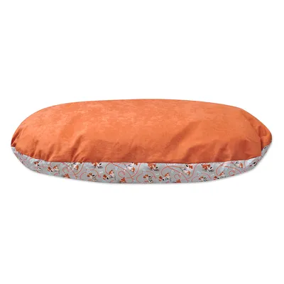 Hundbädd med orange ovansida och kant med mönster av hundar på ljus bakgrund. Tygmaterial synligt.