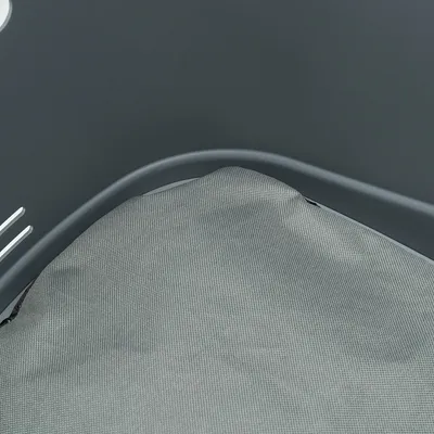 Grå plastikkurv med aftagelig, grå tekstilpude i bunden. Synlige ventilationshuller i siden af kurven.