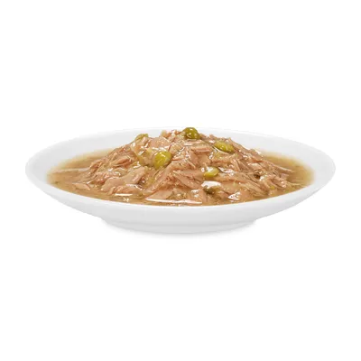 Мокра храна за домашни любимци в бялa чиния, съдържаща месо на парчета в сос с видими зелени грахови зърна.