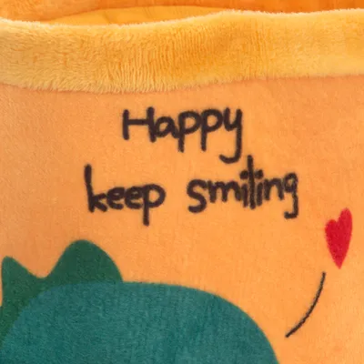 Text na oranžové látce: „Happy keep smiling“ s červeným srdcem a zeleným motivem pod ním.
