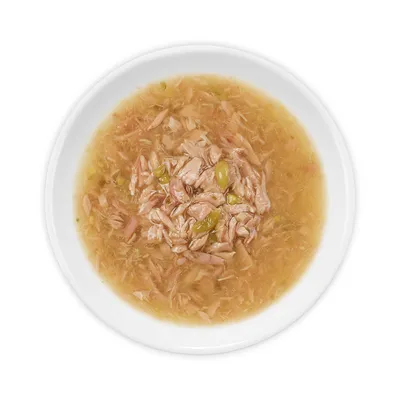 Nahaufnahme einer Schale mit Nassfutter, bestehend aus Fleischstücken und grünen Gemüsestücken in Brühe.