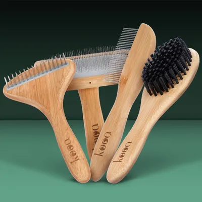 Set di quattro spazzole e pettini per animali con manico in legno kooa, setole metalliche e sintetiche visibili, marchio kooa inciso sui manici.