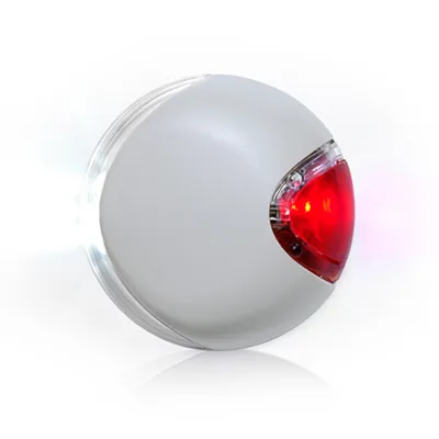 Round device with a red light on one side and a white light on the other, both illuminated, shown against a plain background.