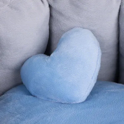 Hartvormig kussen van lichtblauwe pluche stof, geplaatst op een grijze pluchen ondergrond. Materiaal: pluche.