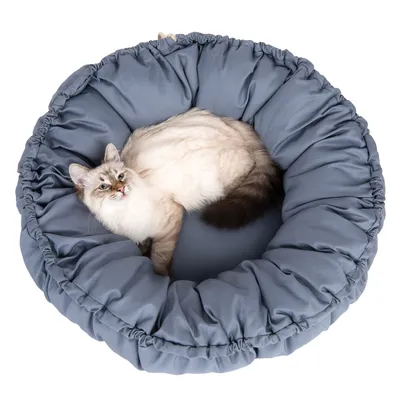 Ronde, gevoerde kattenligplaats in blauw met een kat erop liggend. Toont comfort en design van het product.