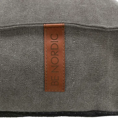 Be Nordic. Detailní pohled na šedý textilní materiál s hnědým koženým štítkem.