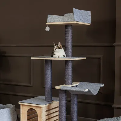 Kratzbaum aus Holz mit grauem Filzbezug, mehreren Ebenen und Sisalstämmen. Katze sitzt auf der oberen Plattform.