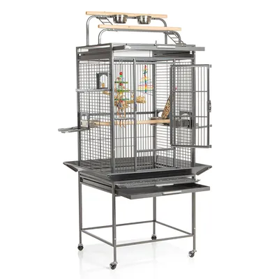 Grande cage à oiseaux en métal avec roulettes, perchoirs en bois, deux gamelles en acier inoxydable sur le dessus, jouets suspendus et plateau amovible visible sous la cage.