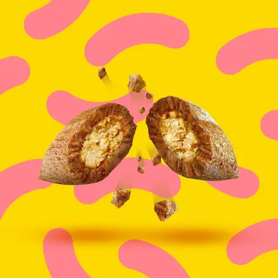 Croqueta partida por la mitad mostrando relleno interior, con trozos pequeños alrededor. Fondo amarillo con formas rosas. No se muestra marca ni texto visible.