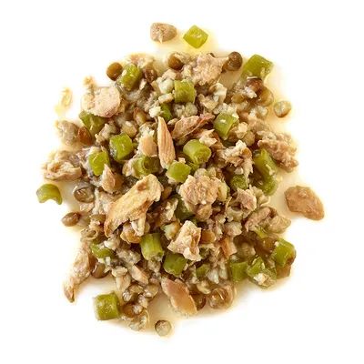 Gemischtes Nassfutter mit Fleischstücken, grünen Gemüsestücken und Soße auf weißem Hintergrund.