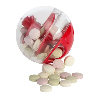 Palla trasparente e rossa in plastica con foro, contenente e distribuendo pastiglie rotonde di vari colori chiaro.