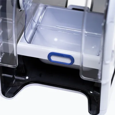 Nahaufnahme einer weissen Schublade mit blauem Griff, Teil eines transparenten Futterautomaten für Haustiere.