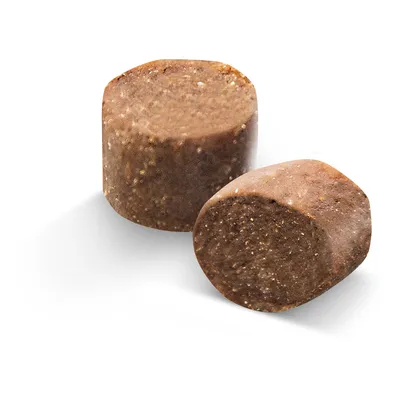 Dos piezas cilíndricas marrones de un producto de alimento para animales con textura granulada visible.