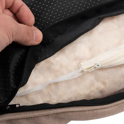 Nahaufnahme eines geöffneten Reissverschlusses mit sichtbarer Füllung aus weichem Material und Netzstoff, geeignet für Kissen oder Polster.