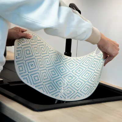 Flexible Matte mit blauem Muster wird unter fliessendem Wasser gereinigt. Geeignet für einfache Reinigung und Wiederverwendung.