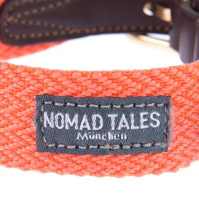 Nomad Tales München. Ετικέτα σε πορτοκαλί υφασμάτινο υλικό με εμφανείς δερμάτινες λεπτομέρειες.