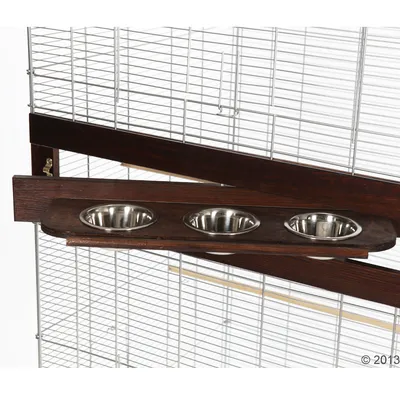 Три метални купички, поставени в дървена стойка, монтирана на решетката на клетка за домашни любимци.