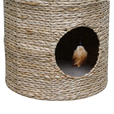 Round cat cave made of woven natural material with entrance opening and hanging feather toy inside.