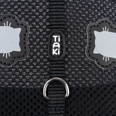 Tiaki logo na čiernej sieťovine s reflexnými motívmi mačiek a kovovým krúžkom.