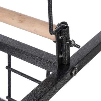 Detailansicht eines Käfigs mit Metallrahmen und Holzstange, zeigt die Befestigung der Stange am Rahmen.