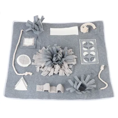 Tapis d’activité en tissu gris et blanc avec plusieurs zones de jeu, cordes nouées, bandes en tissu et ouvertures pour stimuler l’animal. Matériaux visibles : tissu, corde.