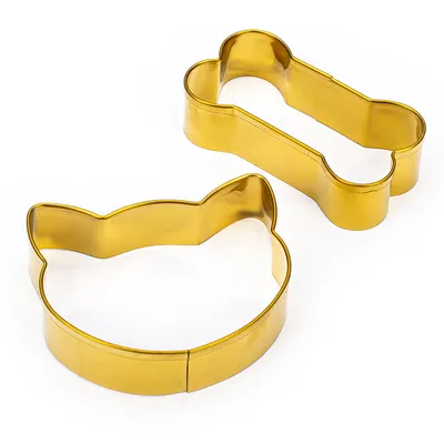 Two gold-coloured cookie cutters, one shaped like a cat's head and one shaped like a bone.
