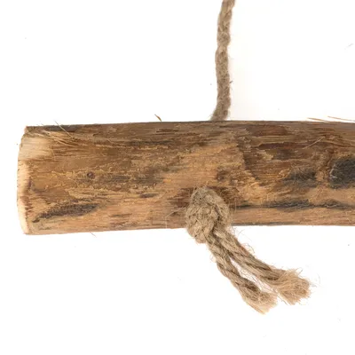 Träpinne med naturligt jutesnöre, lämplig som leksak eller tillbehör. Synlig trästruktur och knut på snöret.