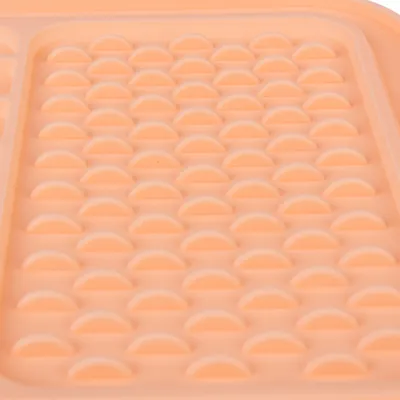 Nahaufnahme einer orangefarbenen Silikonmatte mit halbrunden Erhebungen, geeignet für die Verteilung von Futter oder Snacks.