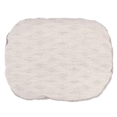 Beige, kvadratisk kudde med flätat stickmönster.